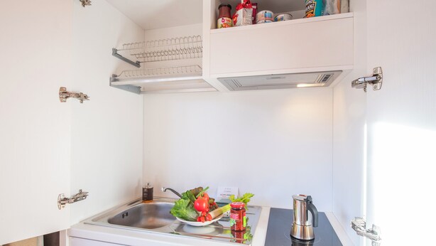 Una kitchenette compacta con un lavamanos, estufa y una pequeña encimera.