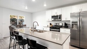 A modern kitchen with white cabinets, stainless steel appliances, and a large island with bar stools.