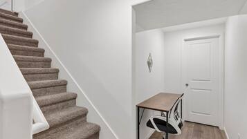 Un escalier avec des marches recouvertes de moquette, une porte blanche et un bureau avec une chaise.