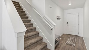 A staircase with carpeted steps, a white handrail, and a white door at the bottom.