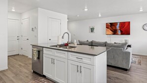 A modern kitchen with white cabinets, a grey countertop, and a built-in sink.