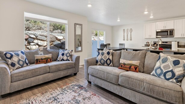 A living room with two sofas, a rug, and a kitchen in the background.