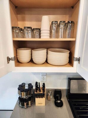 A kitchen cabinet with stacked plates and jars.