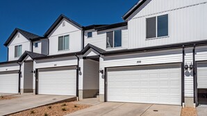 A row of modern, white two-story houses with attached garages, numbered 560 and 558, featuring a clean, suburban architectural style.