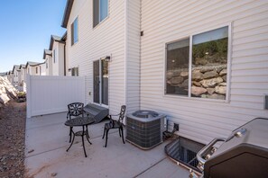 Zona residencial con patio, mobiliario exterior y una parrilla.