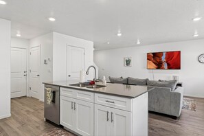 A modern kitchen with white cabinets, a grey countertop, and a built-in sink.
