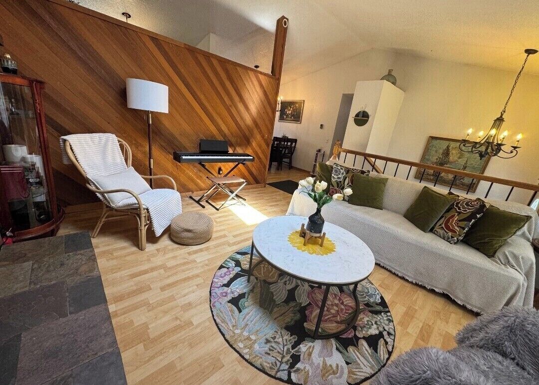 Un salon chaleureux avec un mur en bois, un canapé, un fauteuil, une petite table et une lampe.