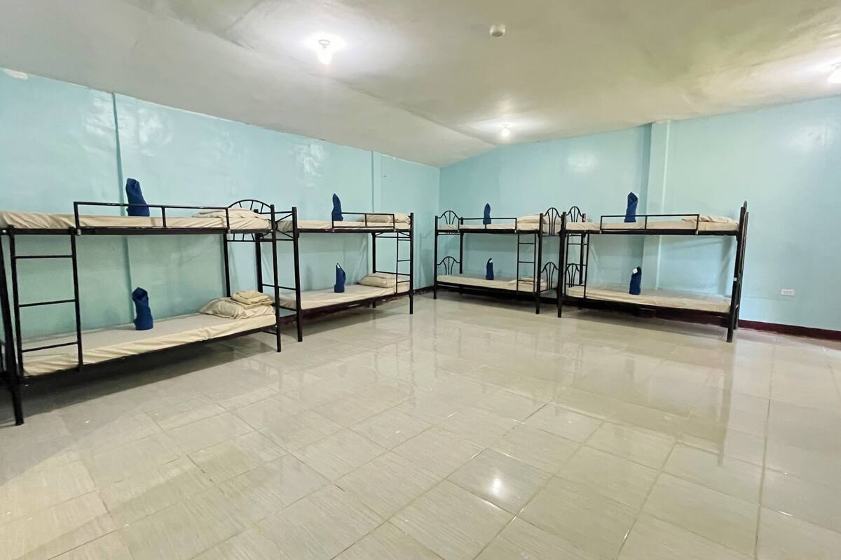 Ein Schlafsaalzimmer mit Etagenbetten, hellblauen Wänden und einem gefliesten Boden.