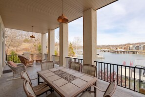 A covered outdoor area with a table and chairs, overlooking a body of water and buildings. - The LOTO Game-Changer: Sand Volleyball Court, No-Wake Cove & a Covered Slip! (Osage Beach)