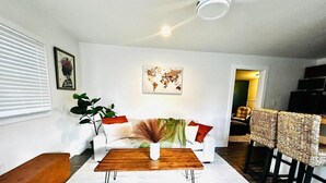Een moderne woonkamer met een witte bank, een houten salontafel en een wereldkaart op de muur.