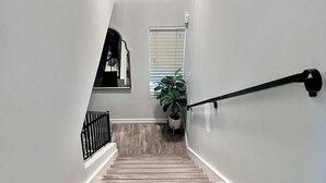 Un escalier avec des marches en bois, une rampe noire et une plante en pot.