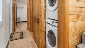 Une buanderie équipée de deux machines à laver, avec des murs en bois, un escalier en bois et un petit coin salon.