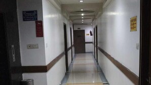 Un long couloir étroit, doté d’un sol à motifs, de murs blancs et d’un plafond pourvu d’un éclairage encastré.
