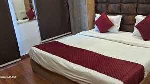 Un lit avec une literie blanche et des oreillers rouges, une tête de lit en bois et une couverture rouge.