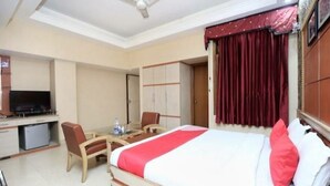 Une chambre d’hôtel comprenant un lit, un bureau avec une chaise, une télévision et une armoire.