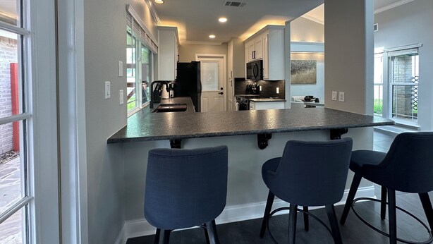 A modern kitchen with a central island, bar stools, and a view of the backyard. - A&C WATERFORD COTTAGE # 1 (Victoria)
