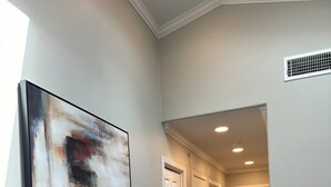A hallway with a modern abstract painting, white doors, and a dark leather chair. - A&C WATERFORD COTTAGE # 1 (Victoria)