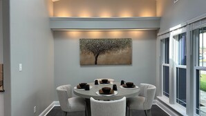 A dining area with a round table, six chairs, and a painting of a tree. - A&C WATERFORD COTTAGE # 1 (Victoria)