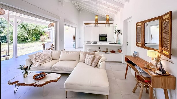 A modern living room with a white sofa, a wooden coffee table, and a desk with a mirror.