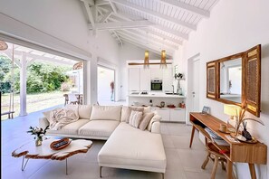 Un salon moderne avec un canapé blanc, une table basse en bois et un bureau agrémenté d’un miroir.