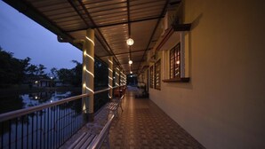 A covered corridor with a wooden floor, metal railings, and a view of a body of water. - Sawasstika Eco Park Resort  (Jalpaiguri)