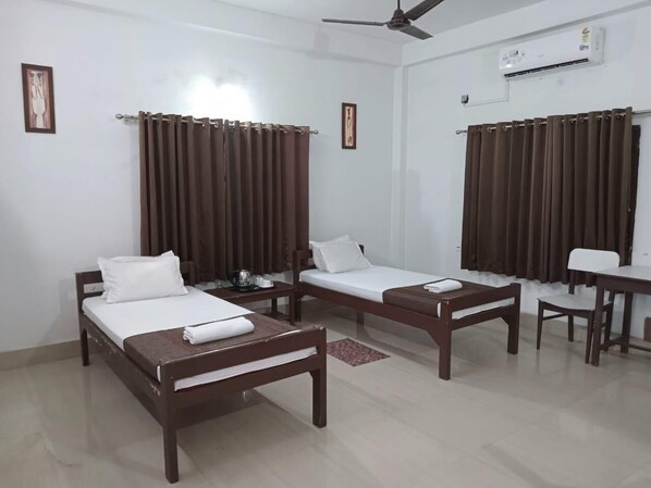 Habitación de hotel con dos camas individuales, una mesita, una silla y un escritorio.