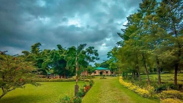 A pathway leading to a building surrounded by lush greenery and trees. - Sawasstika Eco Park Resort  (Jalpaiguri)