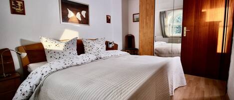 A bedroom with a large bed, wooden headboard, and a wooden wardrobe.