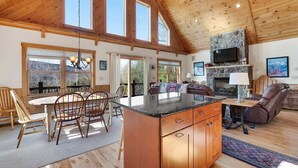 A spacious kitchen with a large island, wooden ceiling, and large windows.