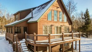 A log cabin with a deck, a covered porch, and a chimney.