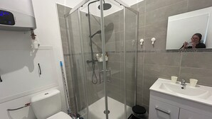 Un bagno moderno con doccia vetro, toilette, lavabo e specchio.