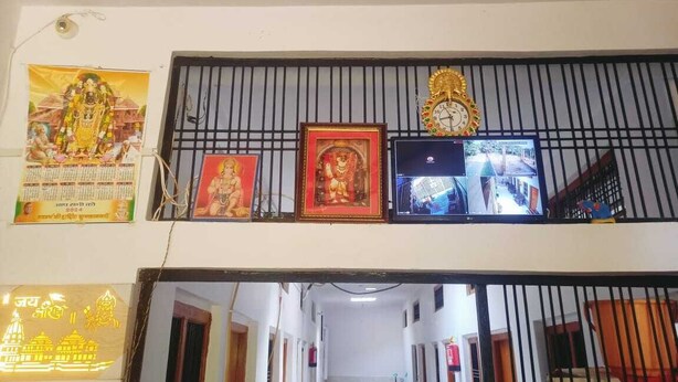 A corridor with a staircase, a clock, and framed pictures on the wall. - Shree Sitaram Guest House (Faizabad)