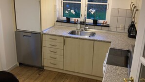 A compact kitchen with a refrigerator, sink, and wooden flooring.