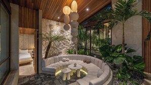 A modern living room with a curved sofa, a coffee table, and a stone wall. - Cala Galeo (Munggu)