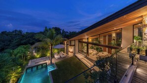 A modern house with a swimming pool, outdoor seating, and lush greenery. - Cala Galeo (Munggu)