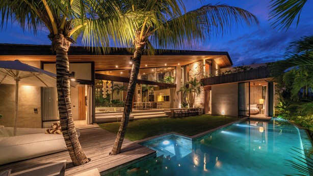 A modern house with a swimming pool, outdoor seating, and palm trees. - Cala Galeo (Munggu)