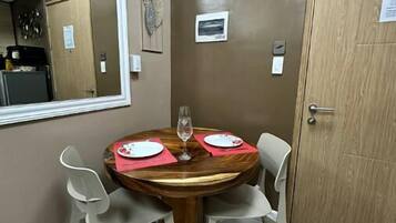A dining area with a round table, four chairs, a wine glass, and a mirror on the wall.