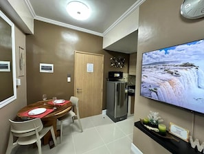 Enjoy meals in the dining area with a table for two and a flat-screen TV displaying a scenic view.