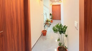 A hallway with wooden doors, potted plants, and wall-mounted lights. - Jay Ambey Palace (Amer)