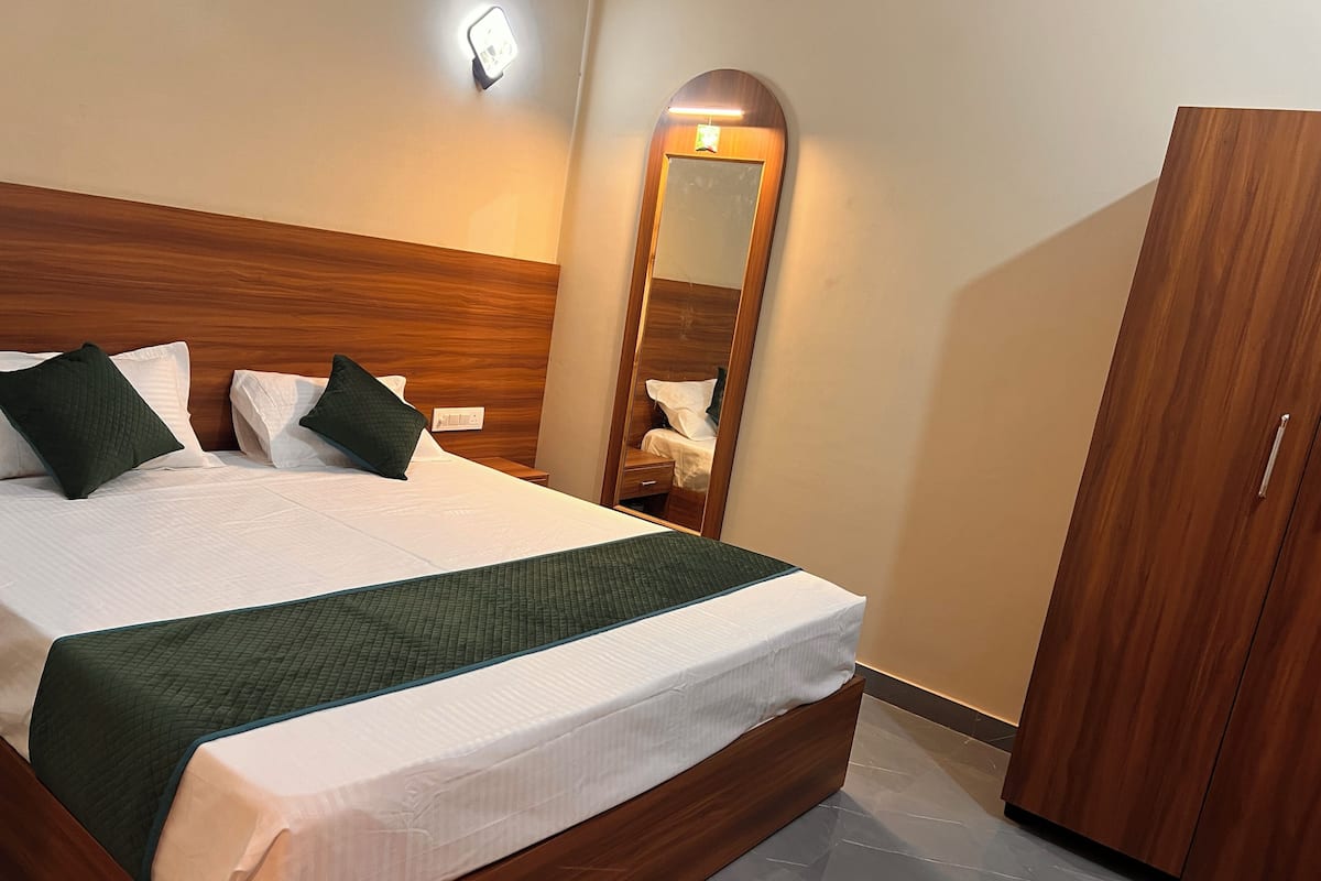 A neatly made bed with a wooden headboard, a mirror, and a wardrobe in a hotel room.