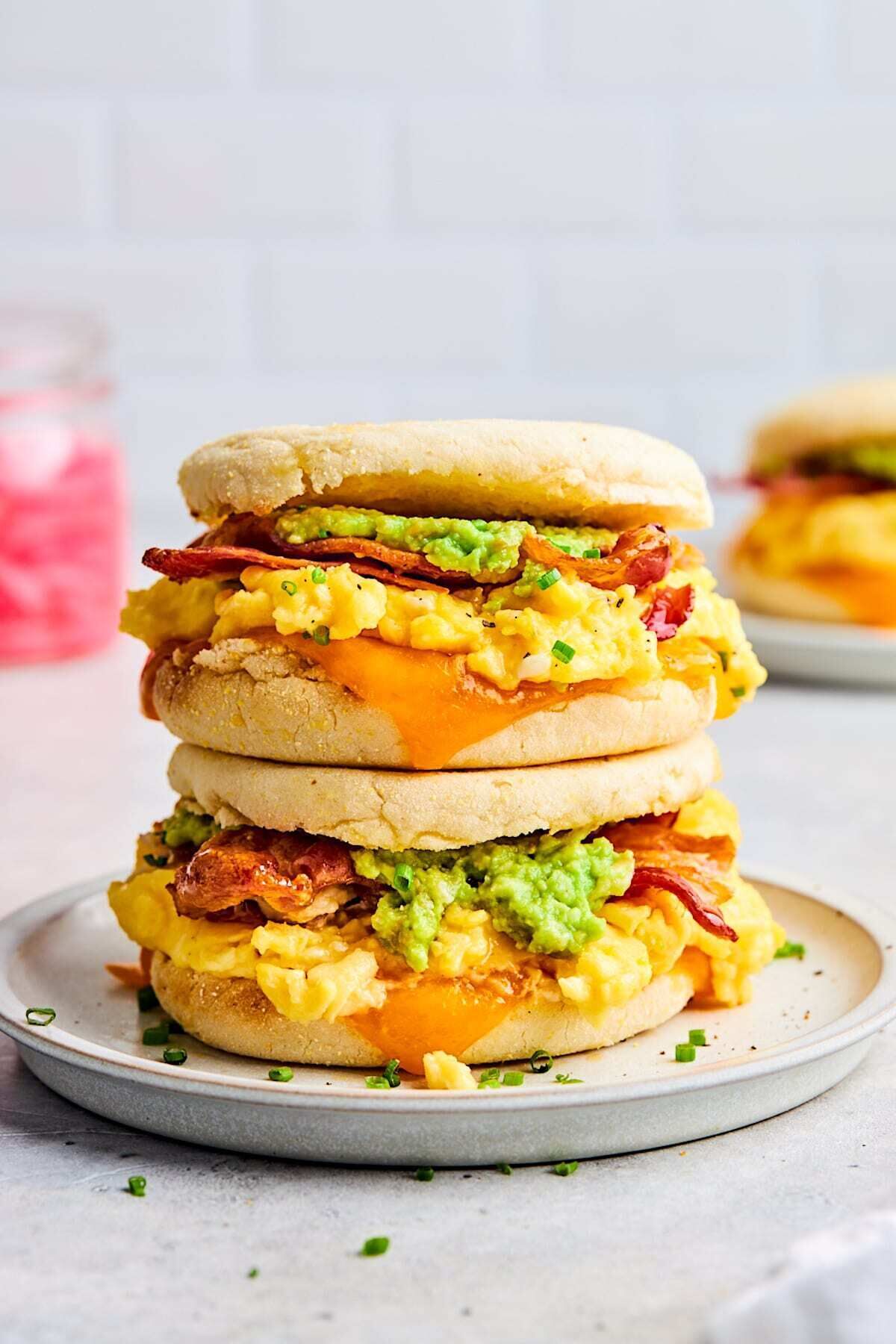 A stack of breakfast sandwiches with avocado, bacon, and cheese.
