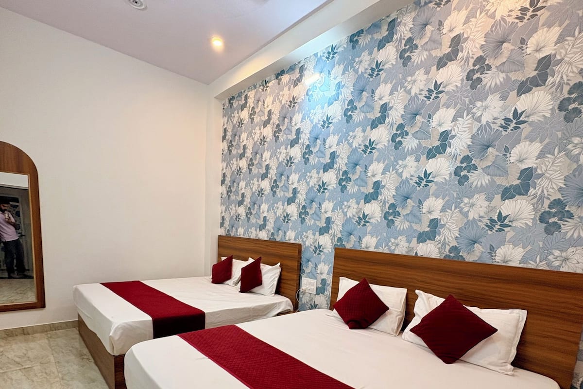 A hotel room with two beds, a ceiling fan, a floral wallpaper, and a marble floor.