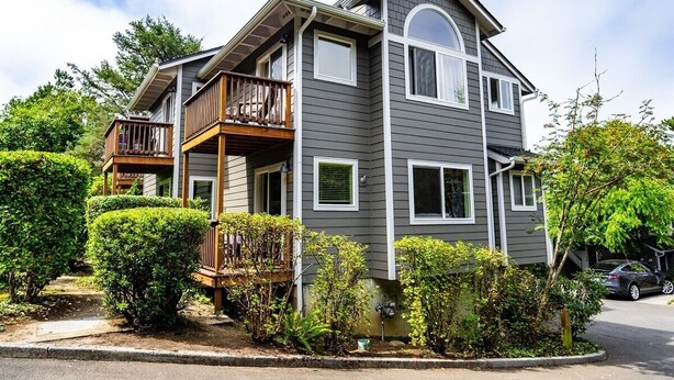 A two-story house with a balcony on the first floor and a garage on the second. - Tolovana 3 - 700ft to Beach - Family Fun - Dogs Ok! (Cannon Beach)