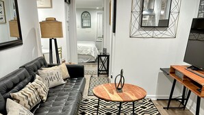 A modern living room with a black leather sofa, a wooden coffee table, and a TV stand. - Charming 1-bedroom, 1 bathroom townhome in awesome Baltimore with WiFi, AC (Baltimore)