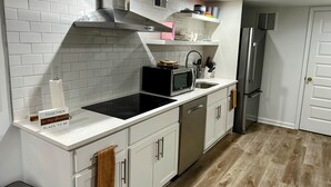 A modern kitchen with white cabinetry, a stainless steel range hood, a microwave, and a refrigerator. - Charming 1-bedroom, 1 bathroom townhome in awesome Baltimore with WiFi, AC (Baltimore)