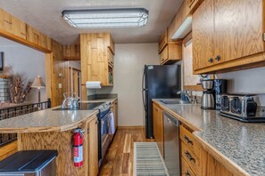 A kitchen with wooden cabinets, a stainless steel refrigerator, a stove, and a coffee maker.