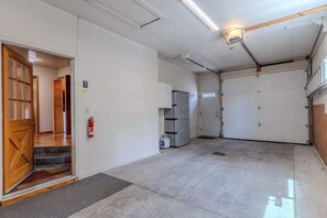 A clean, well-lit garage with a wooden door, a fire extinguisher, and a water heater.
