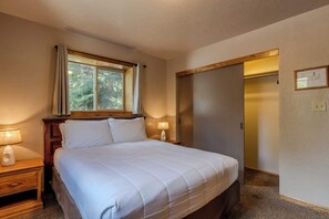 A bedroom with a bed, nightstands, a window with curtains, an elevator, and a framed architectural drawing on the wall.