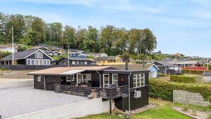 Une maison moderne avec un toit plat, un patio couvert et une cour clôturée.