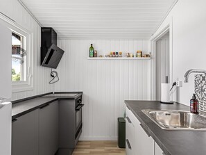 A compact kitchen with a built-in oven, a stainless steel sink, and a window.